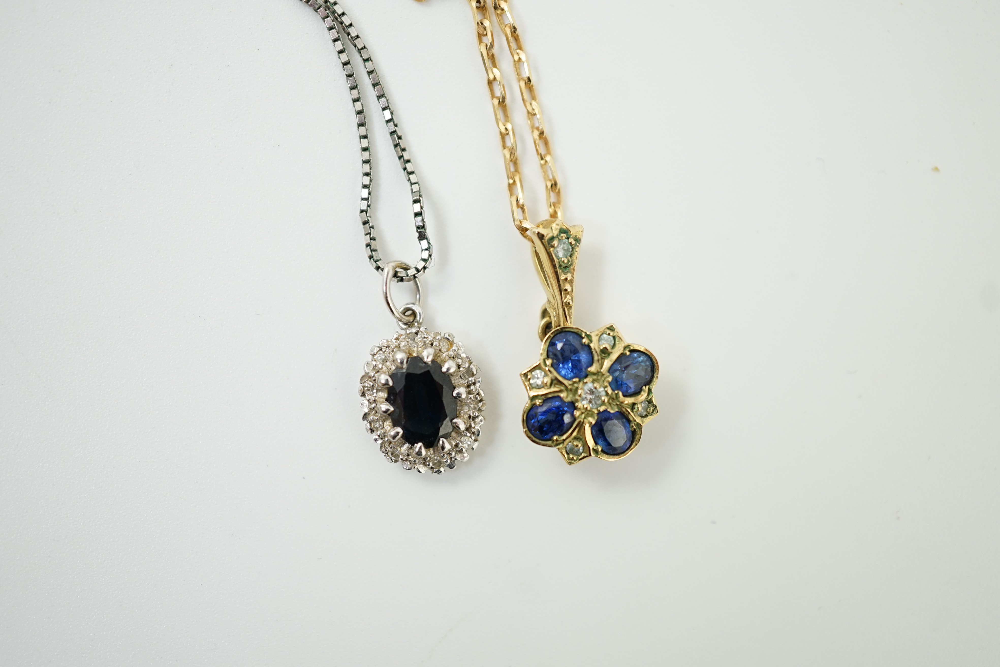 A modern 9ct gold, sapphire and diamond set pendant, overall 19mm, on a 375 chain, 38cm and a similar white metal, sapphire and diamond set pendant, on a 9ct white metal chain, gross weight 7 grams.